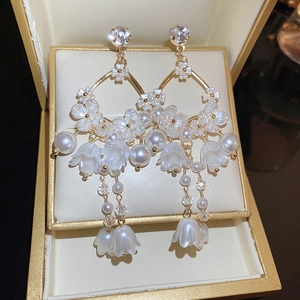 Detailed close-up of lily of the valley earrings with pearls and crystal inlay