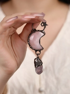 Detail of vintage copper moon pendant with pink and purple crystal on female model