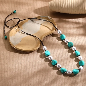 Detail of handmade bohemian necklace with white pearls and turquoise beads on ceramic
