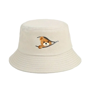 Cream-colored bucket hat featuring a cartoon bear peeking through a zipper print detail