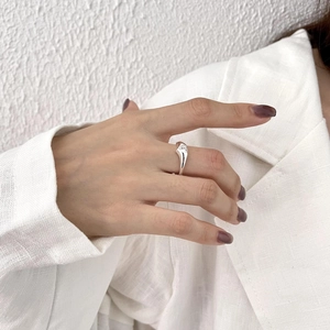 Close-up of minimalist silver open ring with a small zircon on a hand in lifestyle setting