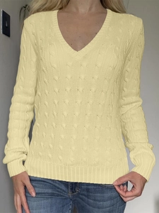Détail d'un pull en maille torsadée jaune pour femme avec col en V et manches longues