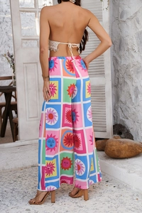 Détail du pantalon large boho avec motifs de visages solaires et carreaux géométriques