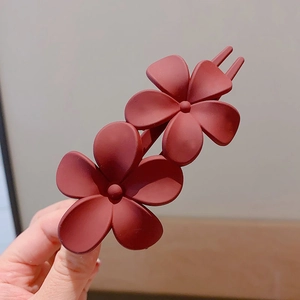 Matte red double flower hair clip for bun hairstyles on a clean background