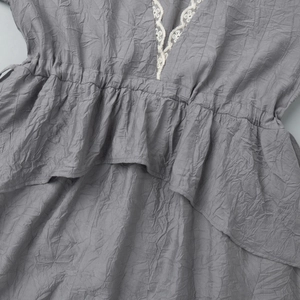 Détail de la robe grise plissée avec dentelle blanche délicate sur le col en V