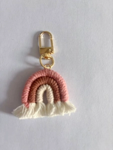 Close-up of handmade macrame rainbow keychain with pink cotton fringes and gold metal clasp