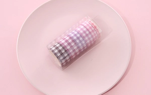 Close-up of 5 rolls of pink and purple plaid washi tape in a clear storage box