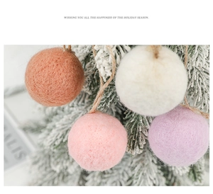 Close-up of multicolored wool felt ball ornaments hanging on a snowy Christmas tree