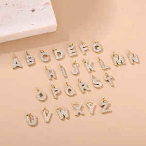 Macro view of 26 gold micro-pave letter pendants with zircon for DIY jewelry making