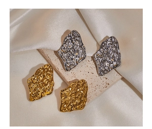 Detailed shot of irregular geometric earrings in gold and silver on champagne satin