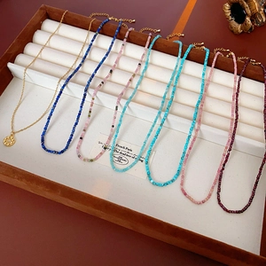 Vue détaillée de colliers de perles colorés et pendentif doré sur un plateau blanc