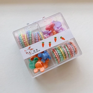 Detail of candy-colored elastic hair ties and mini clips in a transparent four-grid box