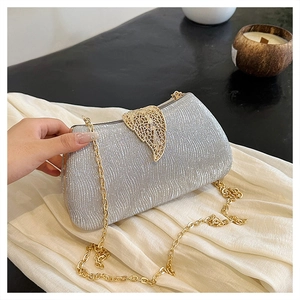 Detail of silver glitter evening clutch bag with golden leaf clasp and chain strap