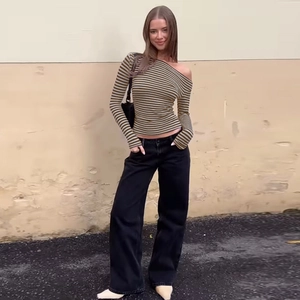 Détail d'une femme portant un haut rayé à une épaule et un pantalon noir à jambes larges