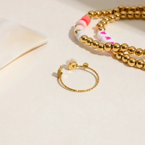 Detail shot of a minimalist gold adjustable flower ring and elegant beaded bracelets