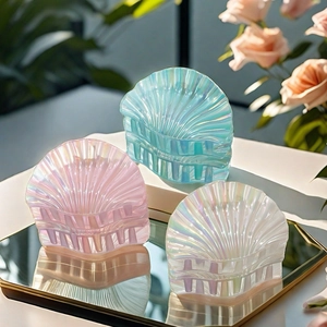 Close-up of three pearlescent shell hair claws in pink, blue, and white colors