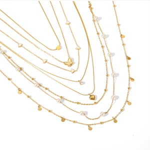 Détail d'un collier multicouche doré avec pendentifs cœur, papillon et perles nacrées