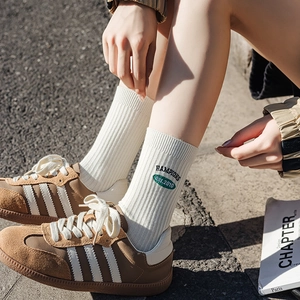 White crew socks with green HAMPIOS embroidery, ribbed style paired with brown sneakers