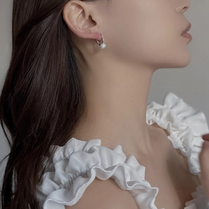 Close-up of model wearing minimalist silver pearl hoop earrings for a classic look