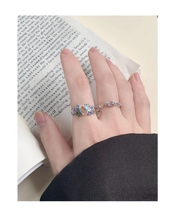 Detailed close-up of S925 silver rings with opal and zircon on an open book