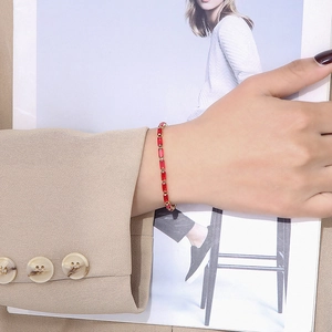 Detailed shot of a gold-plated bracelet featuring continuous baguette-cut red zircons