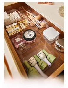 Close-up of clear acrylic drawer organizers storing cosmetics and brushes in a wooden drawer