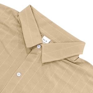 Detail of khaki linen shirt collar with white vertical stripes and resin buttons