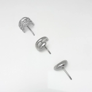 Macro view of three silver stud earrings featuring mesh, ring, and bean shapes