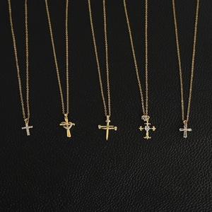 Detail view of five gold cross necklaces with zircon inlays on black leather texture