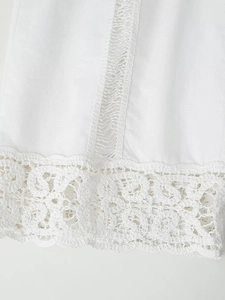 Gros plan de l'ourlet en dentelle crochetée blanche avec motifs géométriques sur le pantalon