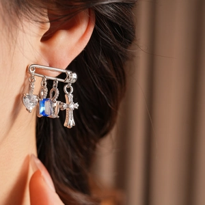 Detailed view of silver pin earrings with blue zircons and cross charms on model