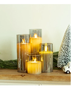 Set of four grey glass LED flameless candles on a wooden table with festive decor