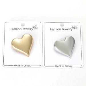 Detailed view of heart-shaped gold and silver pins on white jewelry display cards