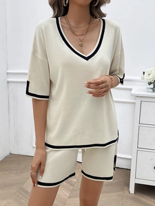 Detail of beige V-neck knit set with black contrast trim and soft ribbed texture