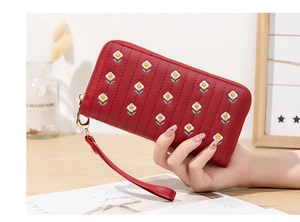Detail view of a long red PU wallet featuring floral embroidery and a wristlet strap