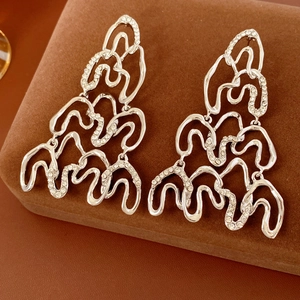 Macro shot of silver wave-shaped drop earrings with diamonds on a luxury jewelry box