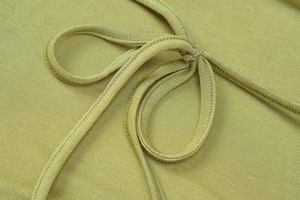 Gros plan sur le tissu en maille côtelée vert moutarde avec un détail de nœud papillon