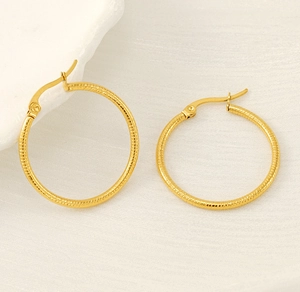 Detail of large gold-plated hoop earrings with elegant spiral texture and secure clasp