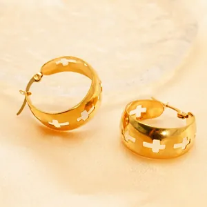 Golden chunky hoop earrings with hollow cross patterns on silk background