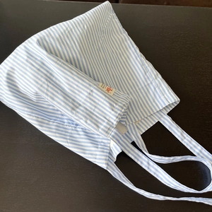 Dettaglio della borsa tote in tela a righe blu e bianche con etichetta tessuta su legno
