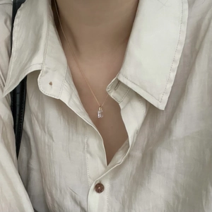 Close-up of elegant gold chain necklace with a clear rectangular crystal on a model