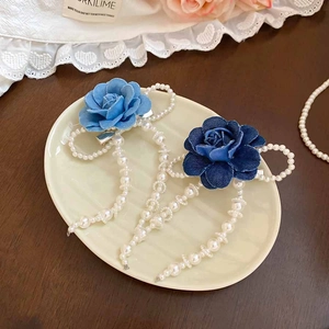 Detailed view of blue fabric rose hair clips with faux pearls and silver duckbill base