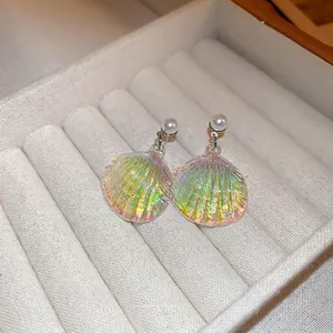 Iridescent shell drop earrings with white pearl studs on a beige velvet jewelry box