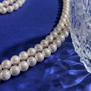 Detailed view of double-layered pearl necklace with smooth luster on blue silk