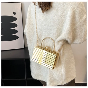 Detail of gold evening clutch with V-shaped texture, pearl clasp and metal chain