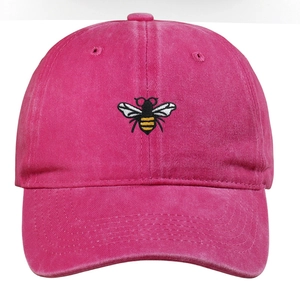 Detailed close-up of a bee embroidery on a vintage washed rose red baseball cap