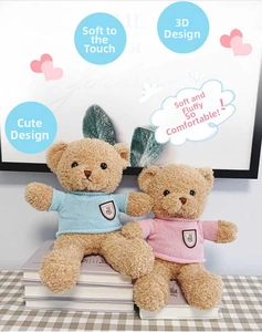 Detail of pink and blue teddy bears with knitted sweaters on a checkered tablecloth