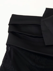 Vue détaillée d'une mini-jupe noire avec patchwork de dentelle et tissu satiné plissé