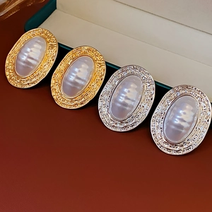 Detail view of oval pearl earrings with gold and silver vintage textured metal frames