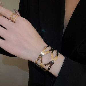 Detailed close-up of hollow geometric gold bangle and matching ring set on a female model